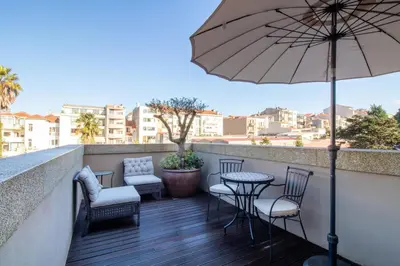 a balcony with chairs and a table and an umbrella at Deluxe Design 1BR w Terrace by LovelyStay in Porto