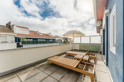 a balcony with two wooden benches and an umbrella at GuestReady- Charming Porto Retreat with Terrace in Porto