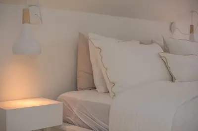 a bed with white sheets and pillows next to a night stand at The Dome in Porto