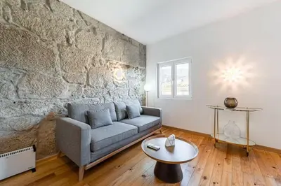 a living room with a couch and a stone wall at Vila Rio Guest House in Vila Nova de Gaia