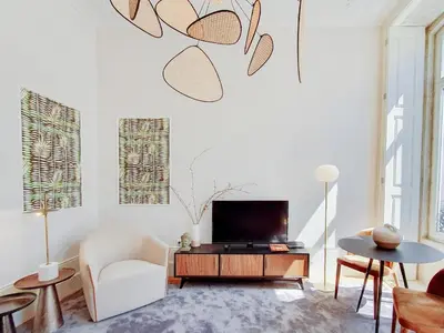 a living room with a tv and a chair at Classic loft in fully renewed building at Batalha in Porto