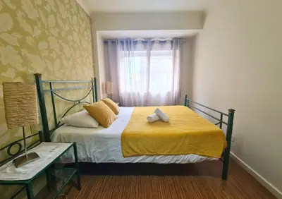 a bedroom with a bed with a yellow blanket and a window at D Joao Premium Suite Bolhao Metro in Porto