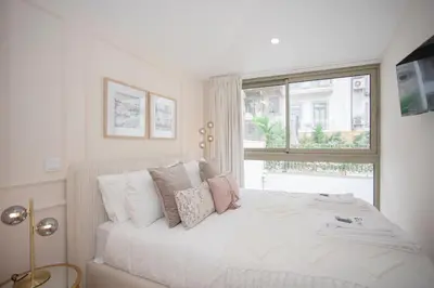 a white bedroom with a bed with pillows and a window at GuestReady - Soho urban retreat in Porto