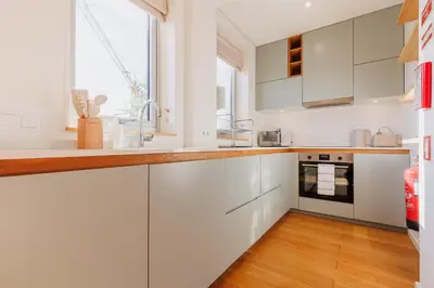 a kitchen with white cabinets and a table and a dining room at Cozee Torrinha in Porto