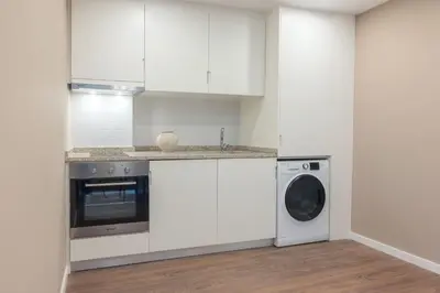 a kitchen with white cabinets and a washing machine at Uma Poveiros in Porto