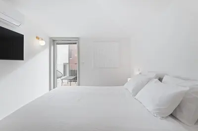 a white bedroom with a white bed with white pillows at Modern 1BR Apartment - Brand New Bonjardim I in Porto
