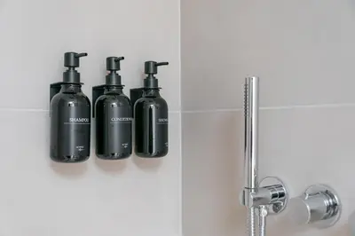 three black bottles on a wall in a bathroom at Stay Bonjardim - Modern Garden Duplex M in Porto