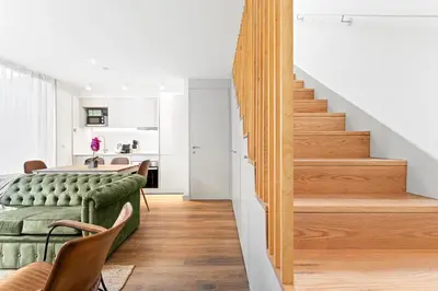 a living room with a green couch and stairs at Stay Bonjardim - Modern Garden Duplex M in Porto