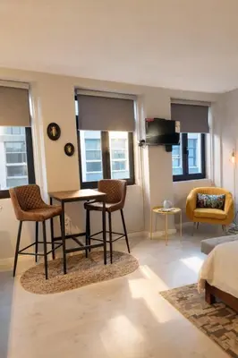 a living room with a table and chairs and windows at Lovely Studio in the Heart of Historic Porto in Porto
