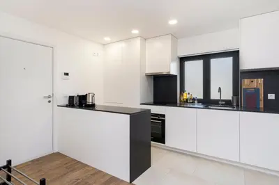 a kitchen with white cabinets and a black counter top at GuestReady - comfort near Jardim do Morro in Vila Nova de Gaia