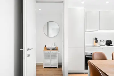 a kitchen with white walls and a table with a mirror at Stay Bonjardim - Modern Garden Duplex N in Porto