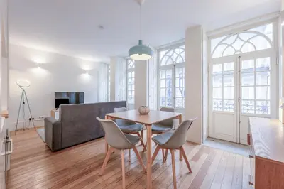 a living room with a table and chairs and a couch at Modern Flat With Balcony on Rua das Flores - 1st in Porto