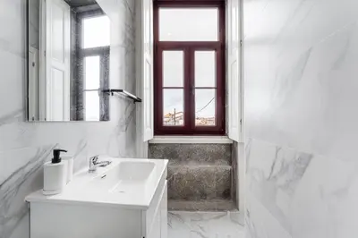 a white bathroom with a sink and a window at GuestReady - Charming Gaia apartment in Vila Nova de Gaia