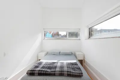 a small bedroom with a bed and two windows at Breiner House Porto in Porto