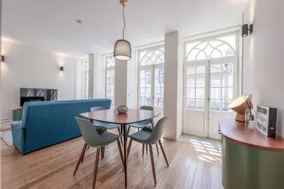 a living room with a table and chairs and a blue couch at Modern Flat with balcony on Rua das Flores - 3rd in Porto