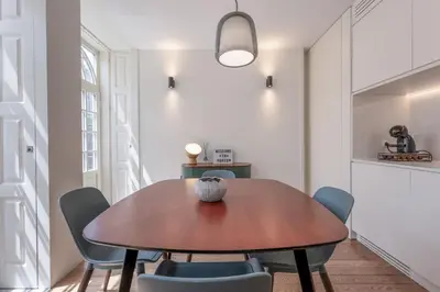 a dining room with a wooden table and blue chairs at Modern Flat with balcony on Rua das Flores - 3rd in Porto