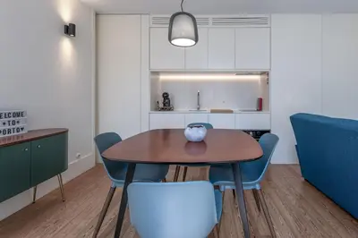 a kitchen with a table and blue chairs in a room at Modern Flat with balcony on Rua das Flores - 3rd in Porto