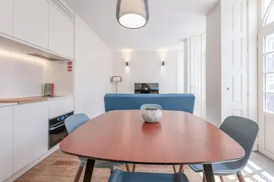 a dining room with a wooden table and blue chairs at Modern Flat with balcony on Rua das Flores - 3rd in Porto