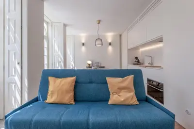 a blue couch with two pillows in a living room at Modern Flat with balcony on Rua das Flores - 3rd in Porto