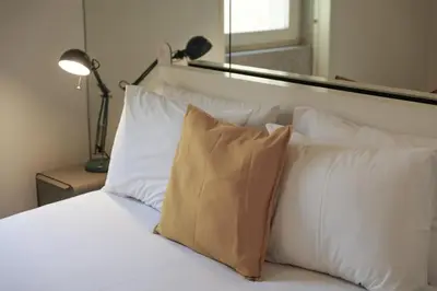 a white bed with white pillows and a mirror at Modern Flat on Rua das Flores - 4th Floor in Porto