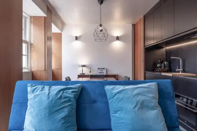 a blue couch in a living room with a kitchen at Modern Flat on Rua das Flores - 4th Floor in Porto