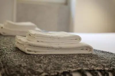 three white towels sitting on a counter in a bathroom at Modern Flat on Rua das Flores - 4th Floor in Porto
