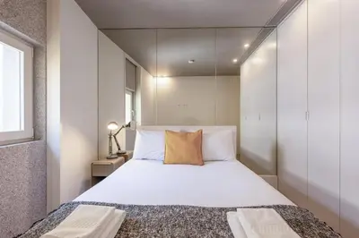 a bedroom with a large white bed with a yellow pillow at Modern Flat on Rua das Flores - 4th Floor in Porto