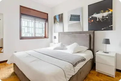 a white bedroom with a large bed and a window at Full 3-Room Apt Downtown Casa do Livro Boavista in Porto