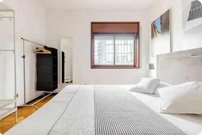 a white bedroom with a large bed and a window at Full 3-Room Apt Downtown Casa do Livro Boavista in Porto