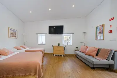 a bedroom with two beds and a couch and a flat screen tv at NEW! House with Hot Tub by Douro River & Iconic Bridge in Vila Nova de Gaia