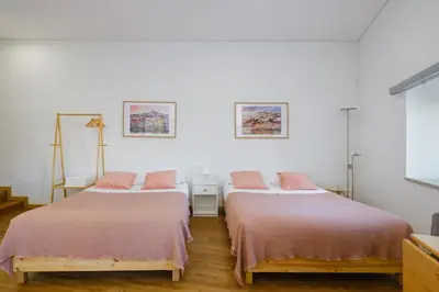 two beds in a room with white walls and wood floors at NEW! House with Hot Tub by Douro River & Iconic Bridge in Vila Nova de Gaia