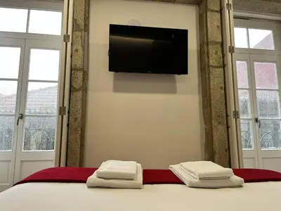 a bedroom with a bed with yellow pillows and a wooden door at Clérigos Cinema Guesthouse in Porto