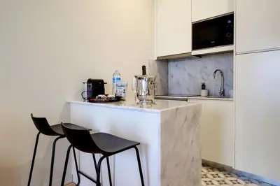 a white kitchen with two chairs and a counter at Luxury Style 5 with AC Downtown Porto near Metro in Porto