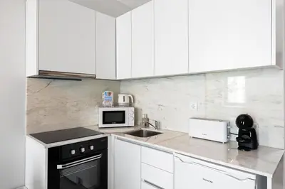 a kitchen with white cabinets and a sink and a microwave at GuestReady - Charming cosy home in Porto