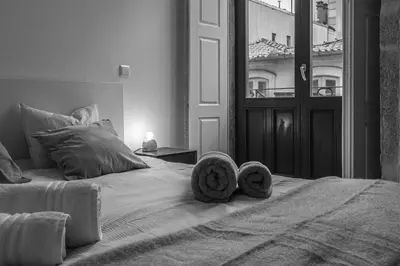 a black and white photo of a bed with towels on it at The Cozy Loft in Porto