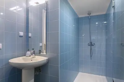 a blue tiled bathroom with a sink and a shower at Egg Nuts Apartment in Porto