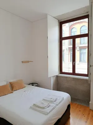 a white bed in a room with a window at Quiet, bright apt near Bolhão in Porto