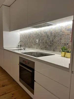 a white kitchen with a sink and a stove at Quiet, bright apt near Bolhão in Porto