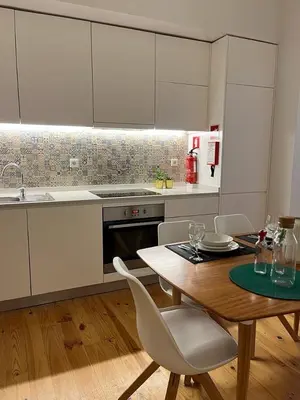 a kitchen with a wooden table and white cabinets at Quiet, bright apt near Bolhão in Porto