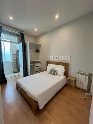 a bedroom with a large bed and a large window at Studio in a typical Porto house in Porto