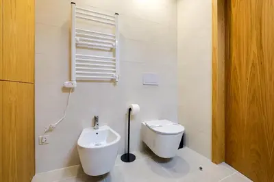 a white bathroom with a toilet and a sink at Camoes Apartment with AC near Metro in Porto