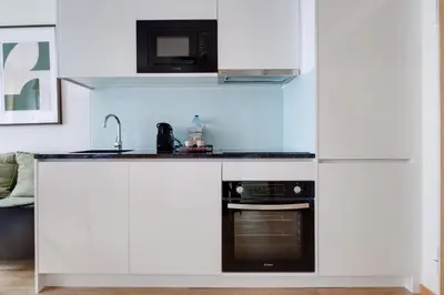 a kitchen with white cabinets and a microwave at Camoes Apartment with AC near Metro in Porto