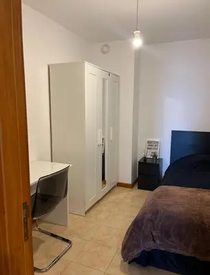 a bedroom with a desk and a bed and a desk and a cabinet at Quarto no centro do Porto in Porto