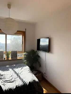 a bedroom with a bed and a flat screen tv on the wall at Quarto grande no centro do Porto in Porto