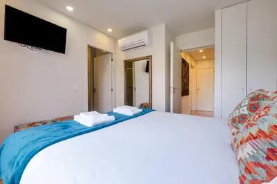a bedroom with a white bed with a tv on the wall at Magnolia 6 Luxury with AC Metro Downtown Porto in Porto