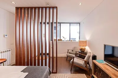 a room with a bed and a chair and a television at Carlos Alberto Apartment in Porto