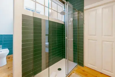 a bathroom with green tiled walls and a glass shower at Urban Refuge 4BD by Vacationy in Porto
