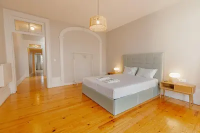 a bedroom with a large white bed and wooden floors at Urban Refuge 4BD by Vacationy in Porto