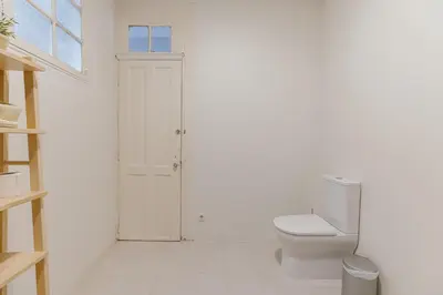 a white bathroom with a toilet and a window at Urban Refuge 4BD by Vacationy in Porto