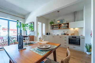 a kitchen with white cabinets and a wooden table at Charming retreat near Boavista with elevator in Porto